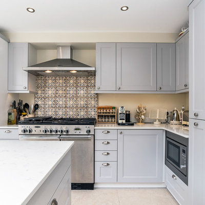 Example of a transitional l-shaped kitchen design in London with recessed-panel cabinets, multicolored backsplash, stainless steel appliances, an island and gray cabinets