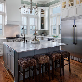 Maritime Küche mit Landhausspüle, Schrankfronten im Shaker-Stil, weißen Schränken, Küchengeräten aus Edelstahl, braunem Holzboden, Kücheninsel, braunem Boden und weißer Arbeitsplatte in New Orleans