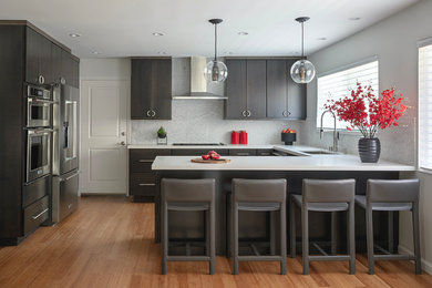 Inspiration for an asian u-shaped bamboo floor and brown floor eat-in kitchen remodel in San Francisco with a single-bowl sink, flat-panel cabinets, dark wood cabinets, quartz countertops, white backsplash, marble backsplash, stainless steel appliances and white countertops