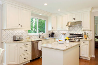 Eat-in kitchen - mid-sized traditional l-shaped medium tone wood floor and brown floor eat-in kitchen idea in Columbus with an undermount sink, raised-panel cabinets, white cabinets, marble countertops, white backsplash, ceramic backsplash, stainless steel appliances and an island