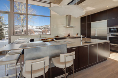 Inspiration for a large contemporary l-shaped light wood floor open concept kitchen remodel in Denver with beige backsplash, stainless steel appliances, an island, flat-panel cabinets, dark wood cabinets, quartz countertops and glass sheet backsplash