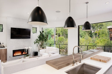 Inspiration for a medium sized contemporary l-shaped open plan kitchen in Denver with a submerged sink, flat-panel cabinets, white cabinets, engineered stone countertops, stainless steel appliances, an island, light hardwood flooring and beige floors.