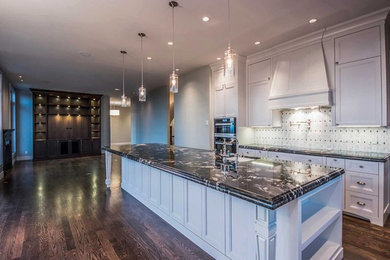 Inspiration for a large classic galley kitchen in Calgary with a submerged sink, shaker cabinets, white cabinets, granite worktops, multi-coloured splashback, marble splashback, stainless steel appliances, dark hardwood flooring, an island and brown floors.