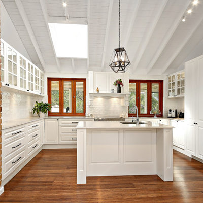 Kitchen - mid-sized transitional u-shaped medium tone wood floor and brown floor kitchen idea in Newcastle - Maitland with a drop-in sink, raised-panel cabinets, white cabinets, white backsplash, stainless steel appliances and two islands