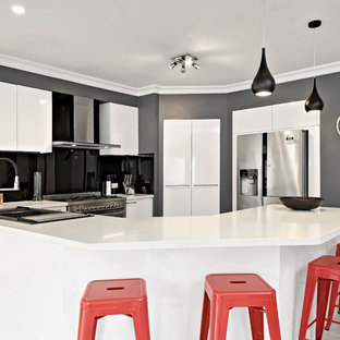 Design ideas for a mid-sized contemporary u-shaped kitchen in Newcastle - Maitland with a double-bowl sink, flat-panel cabinets, white cabinets, quartz benchtops, black splashback, mirror splashback, stainless steel appliances, multiple islands, beige floor and white benchtop.