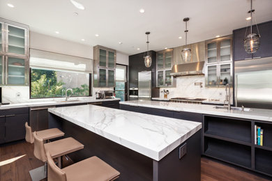 Kitchen - modern medium tone wood floor and brown floor kitchen idea in San Francisco with flat-panel cabinets, dark wood cabinets, white backsplash, stainless steel appliances, two islands and white countertops
