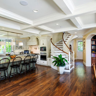 This is an example of an expansive country u-shaped eat-in kitchen in San Francisco with an undermount sink, raised-panel cabinets, beige cabinets, granite benchtops, white splashback, porcelain splashback, stainless steel appliances, medium hardwood floors and brown floor.