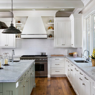 Photo of an expansive traditional u-shaped kitchen in San Francisco with stainless steel appliances, subway tile splashback, marble benchtops, green cabinets, white splashback, an undermount sink, recessed-panel cabinets and light hardwood floors.