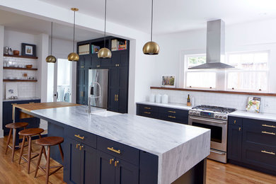 Eat-in kitchen - mid-sized transitional galley medium tone wood floor and brown floor eat-in kitchen idea in Atlanta with a farmhouse sink, shaker cabinets, blue cabinets, marble countertops, white backsplash, ceramic backsplash, stainless steel appliances and an island