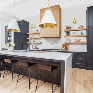 Transitional kitchen ideas - Kitchen - transitional galley light wood floor and beige floor kitchen idea in Atlanta with an undermount sink, shaker cabinets, black cabinets, white backsplash, stone slab backsplash, stainless steel appliances, an island and white countertops
