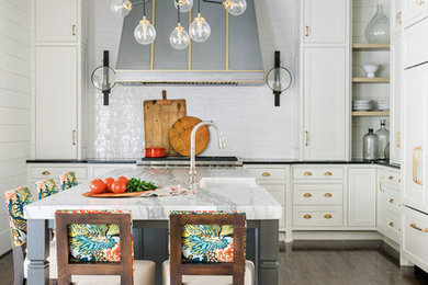 Inspiration for a transitional l-shaped dark wood floor and brown floor kitchen remodel in Atlanta with a farmhouse sink, beaded inset cabinets, white cabinets, white backsplash, subway tile backsplash, paneled appliances, an island and black countertops