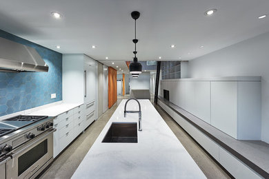 モントリオールにある高級な広いコンテンポラリースタイルのおしゃれなキッチン (アンダーカウンターシンク、フラットパネル扉のキャビネット、白いキャビネット、クオーツストーンカウンター、青いキッチンパネル、セラミックタイルのキッチンパネル、白い調理設備、コンクリートの床、グレーの床) の写真