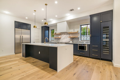 Example of a large trendy l-shaped light wood floor and beige floor kitchen design in Austin with an undermount sink, shaker cabinets, blue cabinets, quartzite countertops, gray backsplash, stone slab backsplash, stainless steel appliances and an island