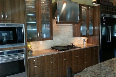 Example of a trendy galley eat-in kitchen design in Philadelphia with an undermount sink, flat-panel cabinets, dark wood cabinets, limestone countertops, black backsplash, stone tile backsplash and colored appliances