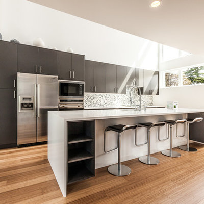 Example of a trendy galley kitchen design in Seattle with flat-panel cabinets, stainless steel appliances, gray cabinets and mosaic tile backsplash