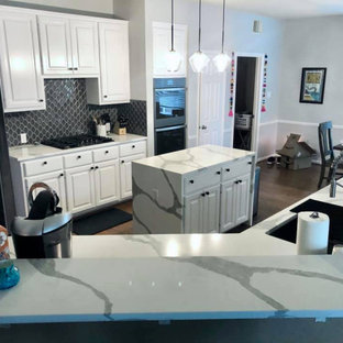 Photo of a small transitional u-shaped eat-in kitchen in Austin with an undermount sink, recessed-panel cabinets, white cabinets, quartz benchtops, blue splashback, ceramic splashback, black appliances, plywood floors, with island, brown floor and multi-coloured benchtop.