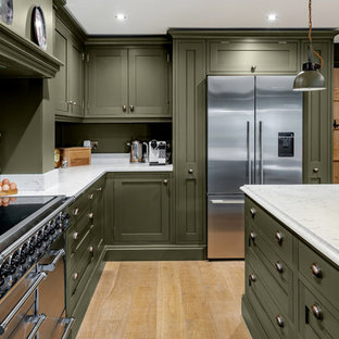 This is an example of a large classic l-shaped kitchen in Other with shaker cabinets, marble worktops, stainless steel appliances, light hardwood flooring, an island, white worktops, green cabinets, green splashback and beige floors.