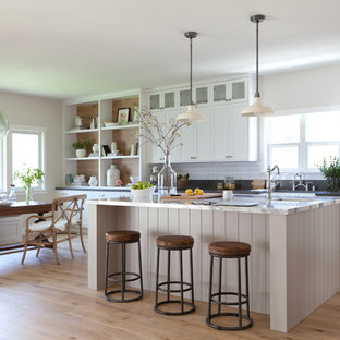Foto de cocina de galera, de estilo de casa de campo, grande, abierta, con armarios estilo shaker, puertas de armario blancas, encimera de mármol, salpicadero blanco, suelo de madera en tonos medios, una isla y salpicadero de azulejos tipo metro