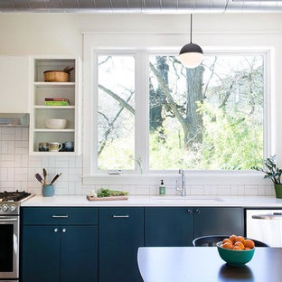 Mid-sized farmhouse eat-in kitchen ideas - Eat-in kitchen - mid-sized farmhouse single-wall dark wood floor and brown floor eat-in kitchen idea in Austin with an undermount sink, flat-panel cabinets, white cabinets, solid surface countertops, white backsplash, porcelain backsplash, stainless steel appliances and no island