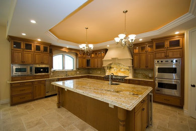 Example of a large transitional u-shaped travertine floor and beige floor enclosed kitchen design in Los Angeles with an undermount sink, recessed-panel cabinets, dark wood cabinets, granite countertops, multicolored backsplash, stone slab backsplash, stainless steel appliances and an island