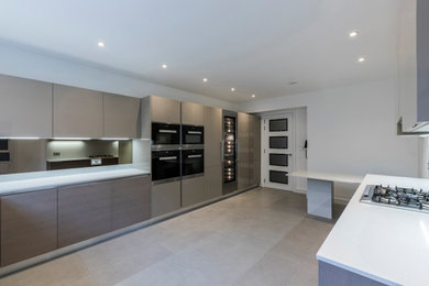 Inspiration for a large modern l-shaped kitchen/diner in London with a built-in sink, flat-panel cabinets, brown cabinets, quartz worktops, metallic splashback, mirror splashback, integrated appliances, porcelain flooring, an island, grey floors, white worktops and a drop ceiling.