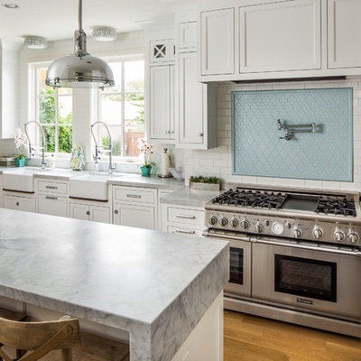 Kitchen - transitional u-shaped kitchen idea in Salt Lake City with a farmhouse sink, shaker cabinets, white cabinets, blue backsplash, subway tile backsplash and stainless steel appliances