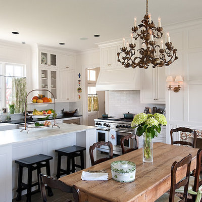 Example of a large classic u-shaped enclosed kitchen design in Dallas with subway tile backsplash, a farmhouse sink, raised-panel cabinets, white cabinets, marble countertops, white backsplash and an island