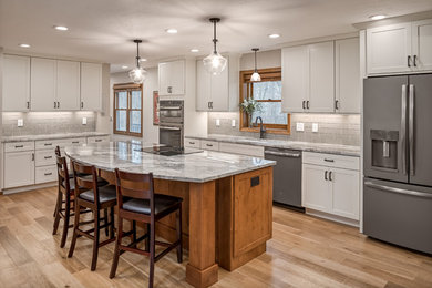 Inspiration for a large l-shaped medium tone wood floor open concept kitchen remodel in Columbus with an undermount sink, shaker cabinets, white cabinets, granite countertops, gray backsplash, subway tile backsplash, an island and gray countertops