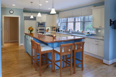 Example of a mid-sized classic l-shaped light wood floor eat-in kitchen design in Bridgeport with an undermount sink, shaker cabinets, white cabinets, granite countertops, blue backsplash, ceramic backsplash, stainless steel appliances and an island