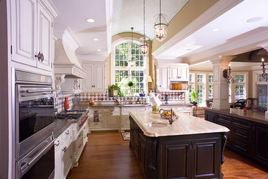 Example of a large classic l-shaped medium tone wood floor eat-in kitchen design in New York with an undermount sink, recessed-panel cabinets, white cabinets, granite countertops, stainless steel appliances and two islands
