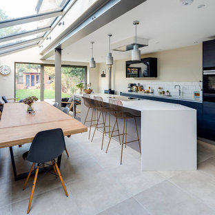 Medium sized contemporary single-wall kitchen in London with a submerged sink, flat-panel cabinets, blue cabinets, stainless steel appliances, slate flooring, an island and grey floors.