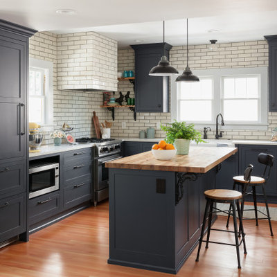 Mid-sized transitional l-shaped light wood floor and brown floor eat-in kitchen photo in Seattle with a farmhouse sink, quartz countertops, an island, subway tile backsplash, paneled appliances, white countertops, recessed-panel cabinets, blue cabinets and white backsplash