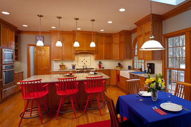 Example of a large transitional l-shaped medium tone wood floor and brown floor eat-in kitchen design in Raleigh with a farmhouse sink, shaker cabinets, medium tone wood cabinets, stainless steel appliances, an island, granite countertops, white backsplash, subway tile backsplash and beige countertops
