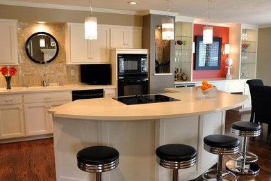 Example of a large trendy l-shaped medium tone wood floor and brown floor open concept kitchen design in Kansas City with beaded inset cabinets, an island, an undermount sink, white cabinets, solid surface countertops, beige backsplash, glass tile backsplash and black appliances