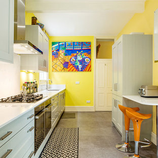 Photo of a mid-sized contemporary galley separate kitchen in London with louvered cabinets, beige cabinets, quartzite benchtops, an undermount sink, white splashback, white benchtop, stainless steel appliances and grey floor.