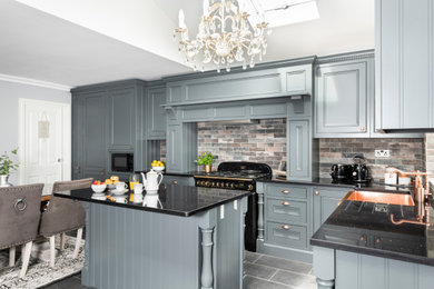 This is an example of a medium sized traditional l-shaped kitchen/diner in Dorset with beaded cabinets, grey cabinets, quartz worktops, stone tiled splashback, an island and black worktops.