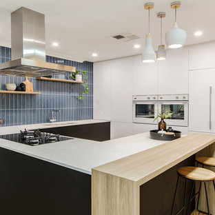 Contemporary u-shaped kitchen in Perth with an undermount sink, flat-panel cabinets, white cabinets, wood benchtops, blue splashback, panelled appliances, medium hardwood floors, a peninsula, brown floor and white benchtop.