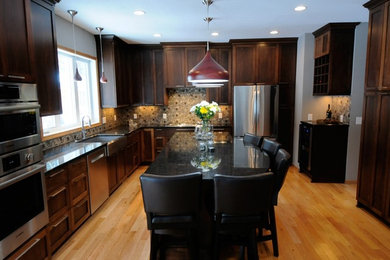This is an example of a large traditional kitchen/diner in Minneapolis with flat-panel cabinets, dark wood cabinets and an island.