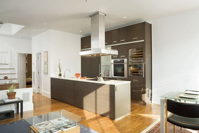 This is an example of a modern galley open plan kitchen in Boston with flat-panel cabinets and brown cabinets.