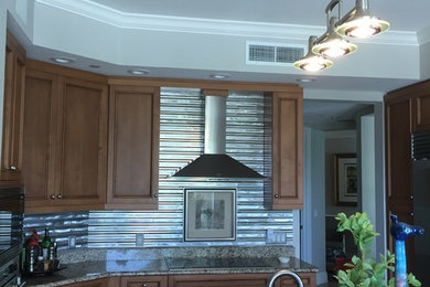 Foto de cocina moderna grande con salpicadero metalizado, salpicadero de metal y una isla