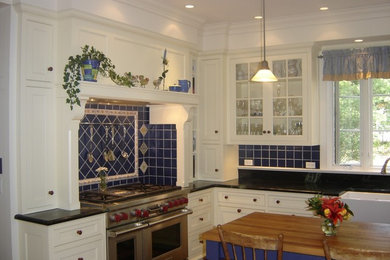 Example of a mid-sized classic l-shaped light wood floor eat-in kitchen design with a farmhouse sink, shaker cabinets, white cabinets, quartzite countertops, blue backsplash, ceramic backsplash, stainless steel appliances and an island