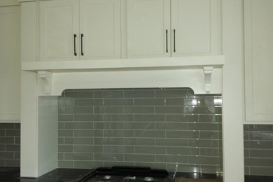 Example of a mid-sized transitional kitchen design in Chicago with recessed-panel cabinets, white cabinets, solid surface countertops, gray backsplash, glass tile backsplash and stainless steel appliances