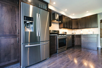 Mid-sized elegant l-shaped medium tone wood floor enclosed kitchen photo in Toronto with an undermount sink, shaker cabinets, brown cabinets, granite countertops, beige backsplash, subway tile backsplash, stainless steel appliances and no island