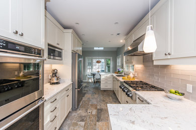 Mid-sized transitional u-shaped porcelain tile and multicolored floor kitchen photo in DC Metro with an undermount sink, shaker cabinets, white cabinets, solid surface countertops, gray backsplash, glass tile backsplash, stainless steel appliances, no island and white countertops