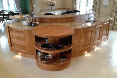 Photo of a contemporary kitchen in Oxfordshire with a submerged sink, raised-panel cabinets, medium wood cabinets, limestone flooring and an island.