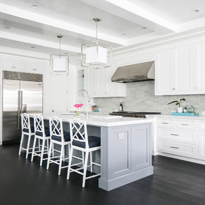 Example of a large beach style l-shaped dark wood floor open concept kitchen design in Orange County with white cabinets, marble countertops, gray backsplash, ceramic backsplash, stainless steel appliances, an island, shaker cabinets and a farmhouse sink
