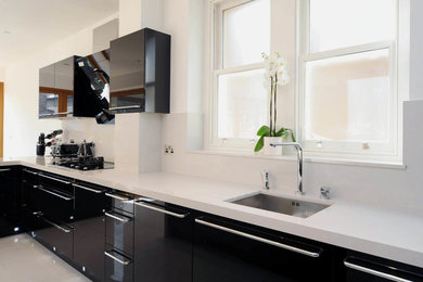 Modern kitchen/diner in London with a single-bowl sink, grey splashback and black appliances.