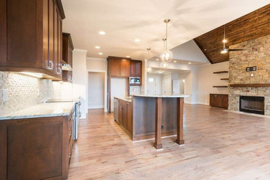 Inspiration for a rustic l-shaped light wood floor and brown floor open concept kitchen remodel in Atlanta with shaker cabinets, dark wood cabinets, granite countertops, beige backsplash, stone tile backsplash and an island