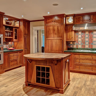 Design ideas for a large arts and crafts l-shaped eat-in kitchen in DC Metro with a farmhouse sink, wood benchtops, recessed-panel cabinets, medium wood cabinets, multi-coloured splashback, ceramic splashback, stainless steel appliances, light hardwood floors, with island and green benchtop.
