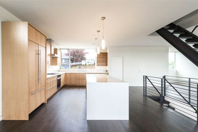 Diseño de cocina minimalista con armarios con paneles lisos, puertas de armario de madera clara, encimera de cuarzo compacto y suelo de madera oscura